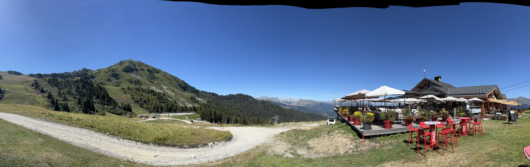 Vue panoramique sur les alpages, la piste et les sommets depuis l'arrivée au Bouc Blanc