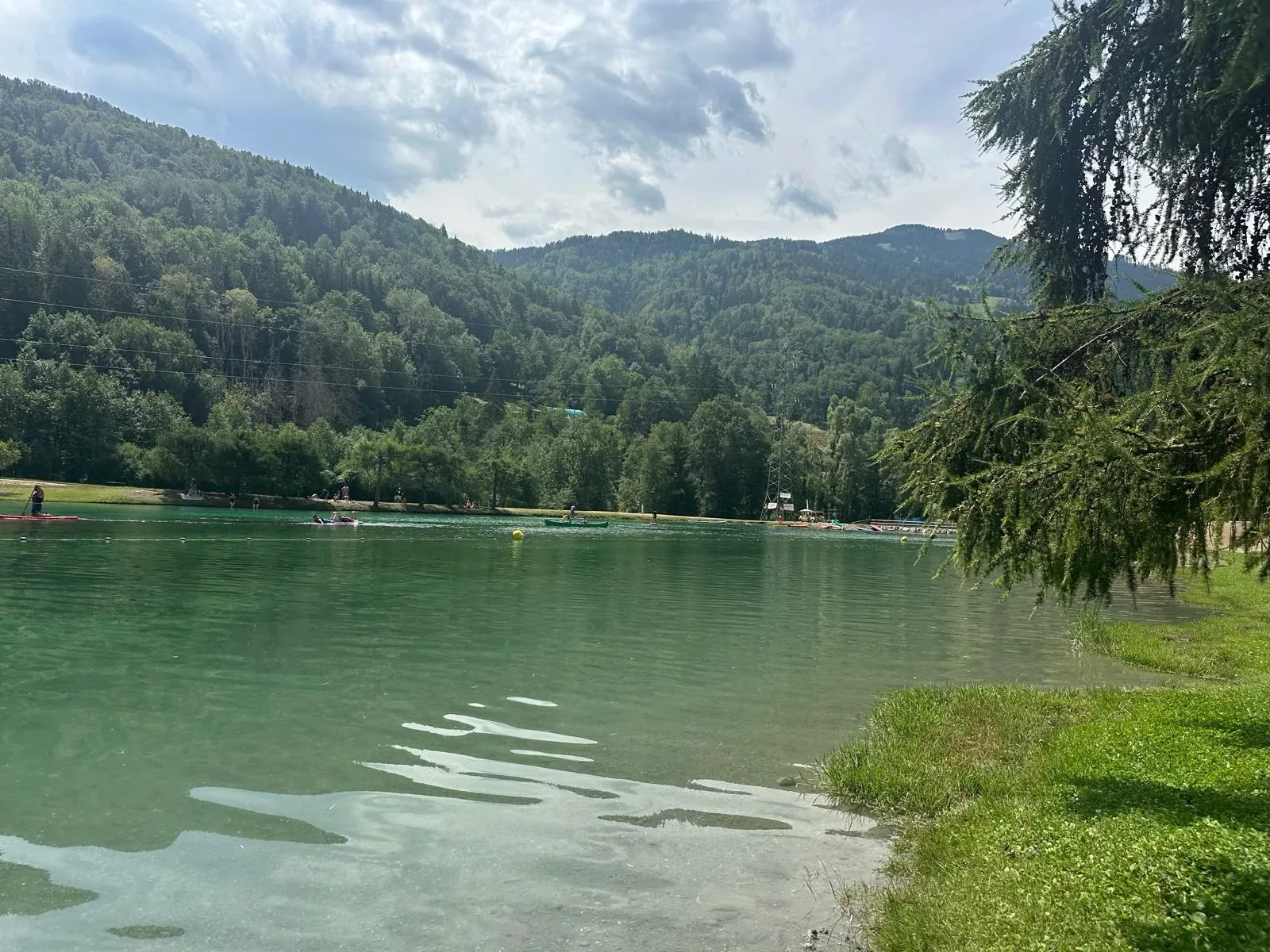Canoes and paddleboards on the Bozel lake, turquoise water and mountain forest