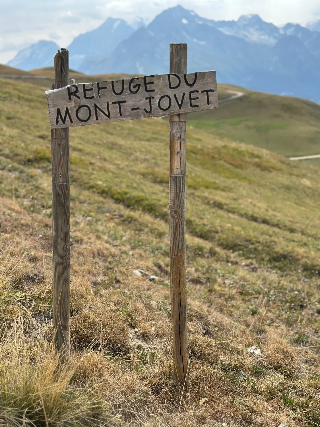 Wooden sign pointing to the Mont Jovet mountain hut, in the high pastures facing the peaks